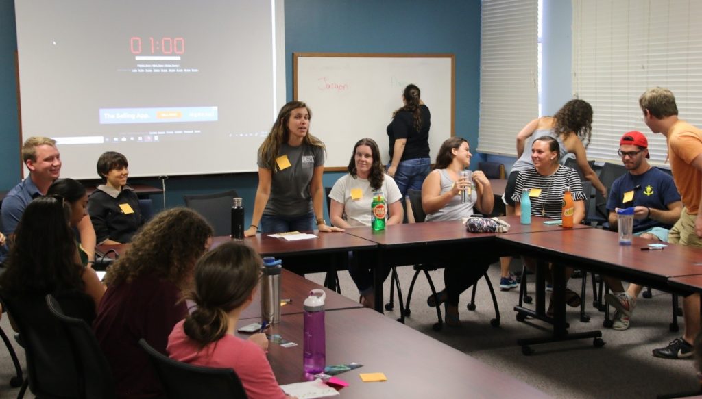 Chelsea Bonnain (standing, center) leads her fellow CMS graduate students in a panel discussion on Communicating Your Science. The group practiced 1-minute, 30-second, and 15-second elevator pitches of their research to the seated REU students.