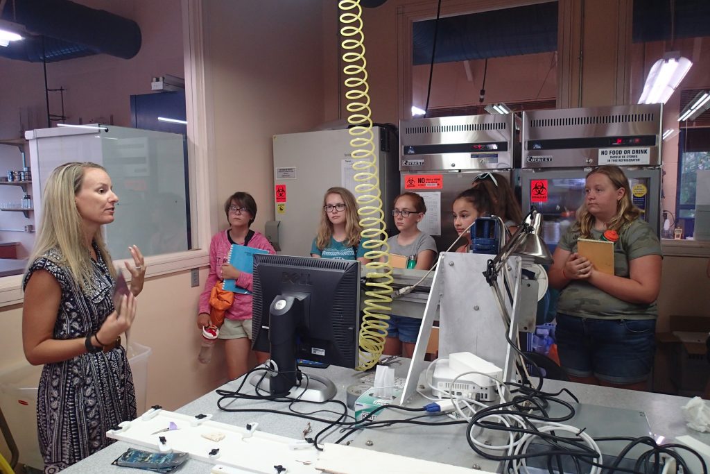 Participants from the Oceanography Camp for Girls listen as Jennifer Flannery (USFCMS Grad ’08) from the USGS explains her work. Photo credit: OCG Staff