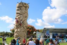 Young climbers take on the rock wall in the foreground of the Poynter Park Stage at the 2018 St. Petersburg Science Festival